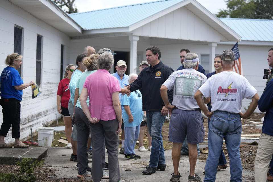 Florida Gov. Ron DeSantis, center, shakes hands with members of the storm-damaged First Baptist Church, as he visits Horseshoe Beach, Fla., one day after the passage of Hurricane Idalia, Thursday, Aug. 31, 2023. (AP Photo/Rebecca Blackwell)