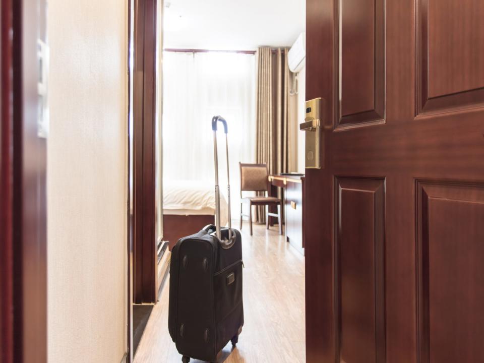 view of wheely suitcase inside a bright hotel room