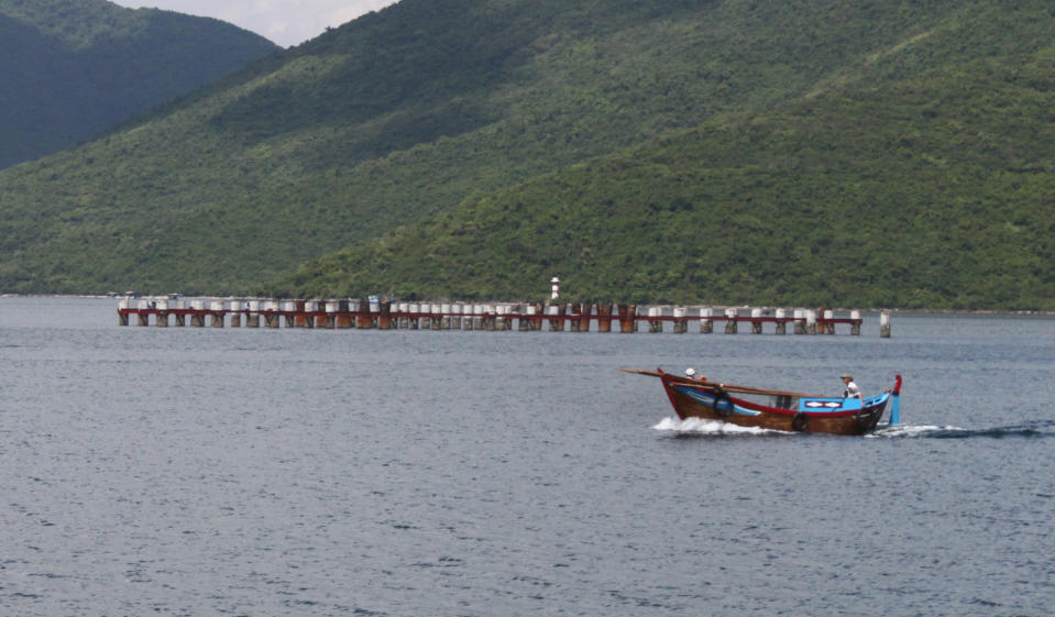 In this photo taken Oct. 17, 2011, a boat passes by the abandoned Van Phong port in Khanh Hoa provinvce in southern Vietnam. All that remains of a plan by Vietnam to build a major deep water port is 114 exposed pilings trailing into the South China Sea and a barge full of rusty machinery. Foreign investors stayed away from the $3.6 billion project and the indebted state-owned company overseeing it bungled the job. Earlier this month, Sept., 2012, the government accused the company of "financial incompetence" and suspended the project. The prospects for ever reviving it are dim. (AP Photo/TuoI Tre Newspaper, Van Ky) VIETNAM OUT