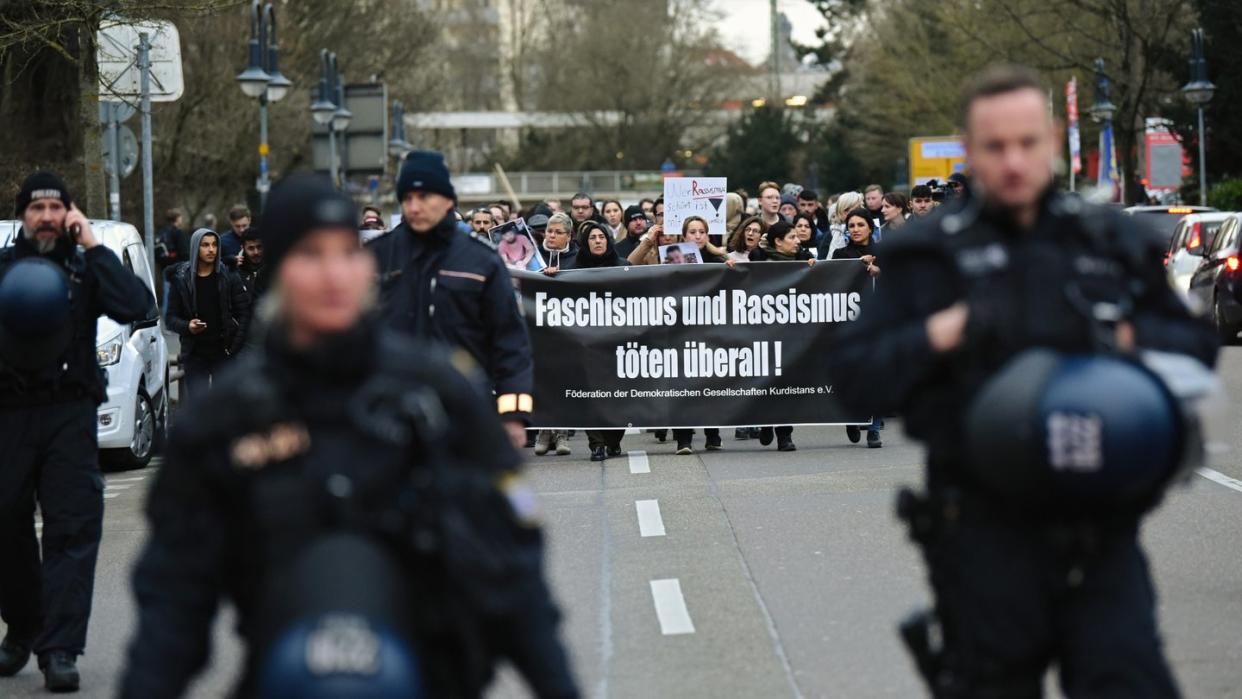 Zahlreiche Menschen laufen in Hanau während eines Trauermarsches vom Tatort Heumarkt zum Tatort Kurt-Schumacher-Platz.