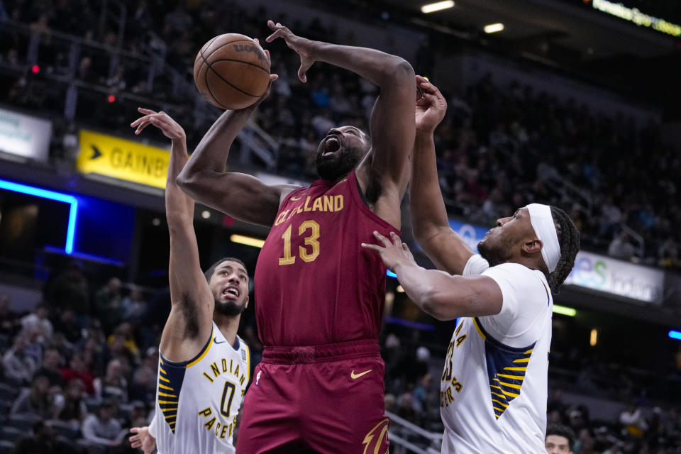 Cleveland Cavaliers center Tristan Thompson (13) looses the ball as he shoots between Indiana Pacers guard Tyrese Haliburton (0) and center Myles Turner (33) during the first half of an NBA basketball game in Indianapolis, Monday, March 18, 2024. (AP Photo/Michael Conroy)