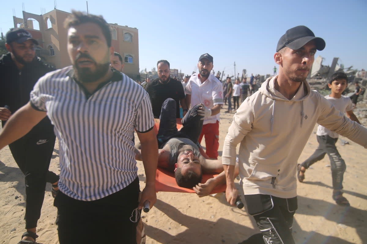 Palestinians carry an injured man from the rubble of a collapsed building after an airstrike in Rafah, in the Gaza Strip (AP)