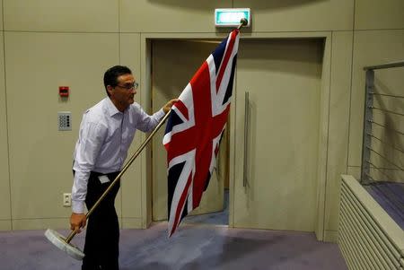 An official carries a Union Jack flag ahead of a news conference by Britain's Secretary of State for Exiting the European Union David Davis and European Union's chief Brexit negotiator Michel Barnier in Brussels, Belgium July 20, 2017. REUTERS/Francois Lenoir