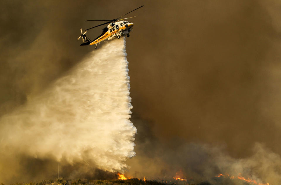 <p>A helicopter makes a drop on a wildfire near Placenta Caynon Road in Santa Clarita, Calif., July 24, 2016. (AP Photo/Ringo H.W. Chiu)</p>