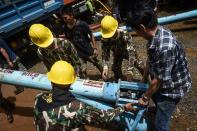 <p>Technicians lift water pumps to the drilling site near Tham Luang Cave in Chiang Rai Province on July 1, 2018, as the rescue operation continues for a missing children’s soccer team and their coach. (Photo:Lillian Suwanrumpha/AFP/Getty Images) </p>