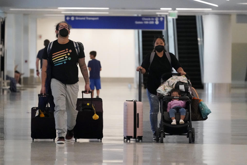 Travelers roll their luggage at a baggage claim area at Los Angeles International Airport Monday, April 25, 2022, in Los Angeles. A week earlier, a federal judge in Florida struck down the requirement to wear a mask in airports and during flights. That rule, designed to limit the spread of COVID-19, was due to expire anyway on May 3. (AP Photo/Marcio Jose Sanchez)