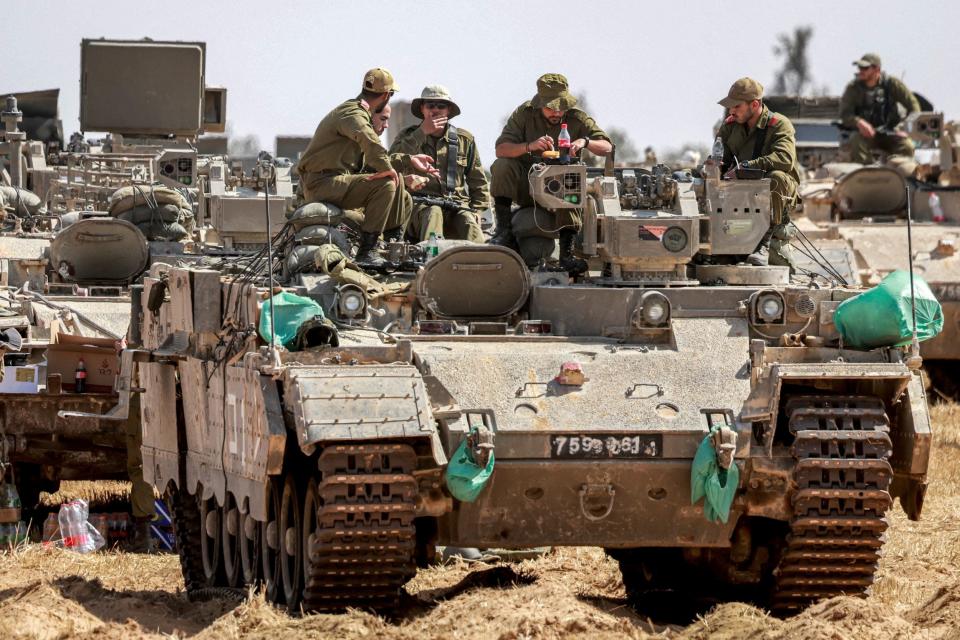 Israeli army soldiers sit atop an infantry-fighting vehicle (IFV) stationed at a position near the border with the Gaza strip