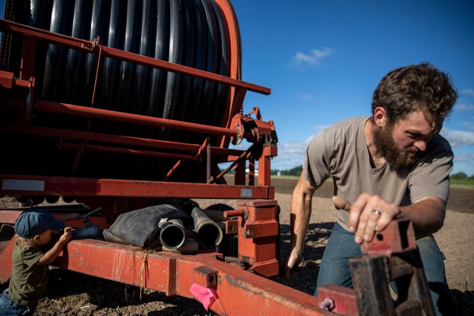 Damien, de casi 2 años, imita a su padre Graham Fordyce mientras configura el riego con una máquina Ag-rain en Fordyce Farm en Salem. Regar los campos lleva 4 horas a la semana.