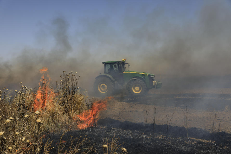 Israeli farmer battles fire started by an incendiary device launched from Gaza Strip, near the Israel and Gaza border fence, Wednesday, May 15, 2019. Palestinians are marking the 71st anniversary of their mass displacement during the 1948 war around Israel's creation. Demonstrations were held across the Israeli-occupied West Bank and the Gaza Strip on Wednesday to mark what the Palestinians call the "nakba," or "catastrophe." (AP Photo/Tsafrir Abayov)