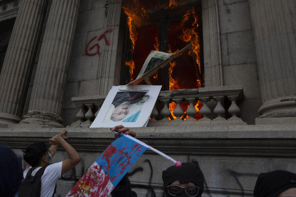 An official photo of former Congress President Eduardo Meyer is thrown out from the Congress building after protesters set a part of the building on fire, in Guatemala City, Saturday, Nov. 21, 2020. Hundreds of protesters were protesting in various parts of the country Saturday against Guatemalan President Alejandro Giammattei and members of Congress for the approval of the 2021 budget that reduced funds for education, health and the fight for human rights. (AP Photo/Oliver De Ros)