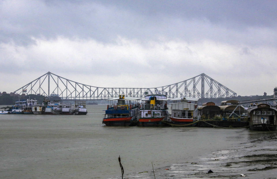 Mechanized boats used to ferry passengers are moored together to avoid losses under the inclement weather due to Cyclone Yaas in Kolkata, India, Wednesday, May 26, 2021. City heritage landmark Howrah Bridge is seen behind. Heavy rain and a high tide lashed parts of India's eastern coast as a cyclone pushed ashore Wednesday in an area where more than 1.1 million people have evacuated amid a devastating coronavirus surge. (AP Photo/Bikas Das)