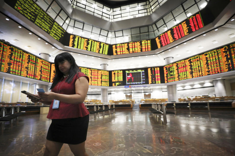 An investor walks in front of stock trading boards at a private market gallery in Kuala Lumpur, Malaysia, Tuesday, July 9, 2019. Asian shares mostly fell Tuesday in quiet trading as investors waited for signs on what might be ahead for U.S. interest rates. (AP Photo/Vincent Thian)