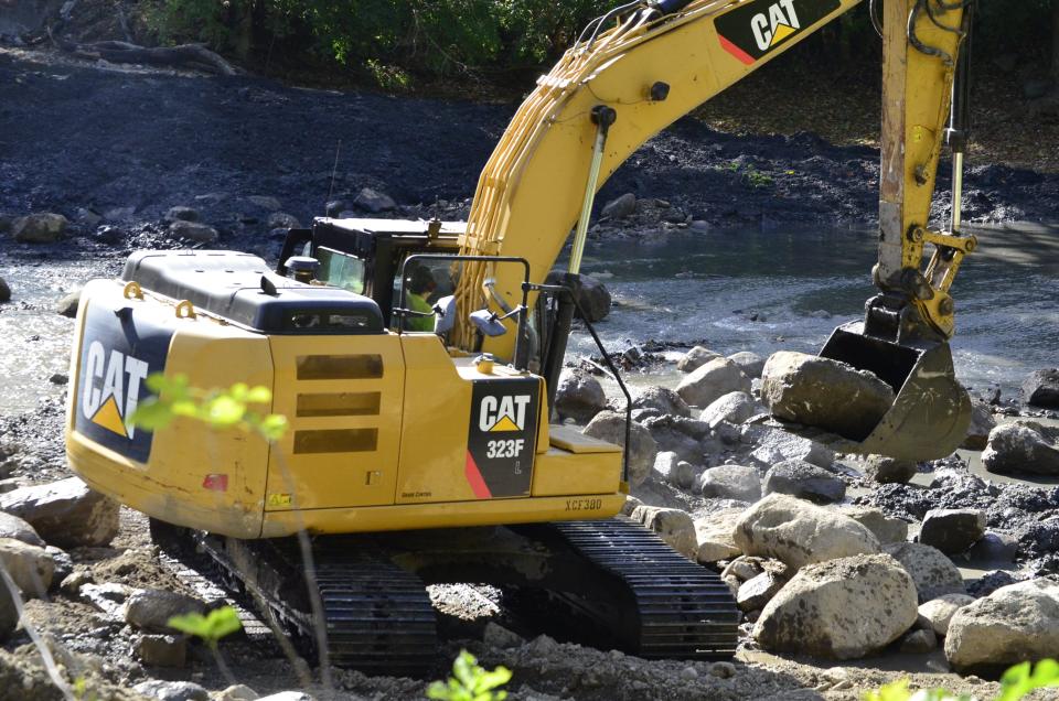 A city worker removes a rock that made up part of Weir Dam on the Whitewater River in Richmond, Wednesday, Oct. 4, 2023.