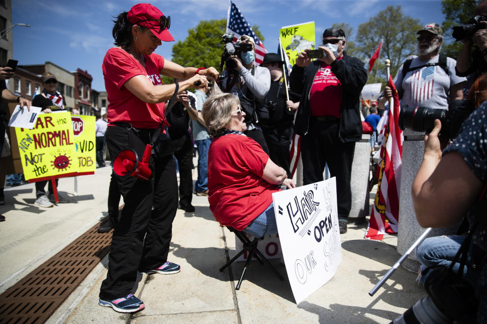 FILE - In this May 15, 2020, file photo, hairdresser Bridget Nowak cuts Elizabeth Castelli's hair during a rally against Pennsylvania's coronavirus stay-at-home order at the state Capitol in Harrisburg, Pa. Hair salons have become a symbol for small business owners who are eager to reopen after the long lockdowns to fight the coronavirus. (AP Photo/Matt Rourke, File)