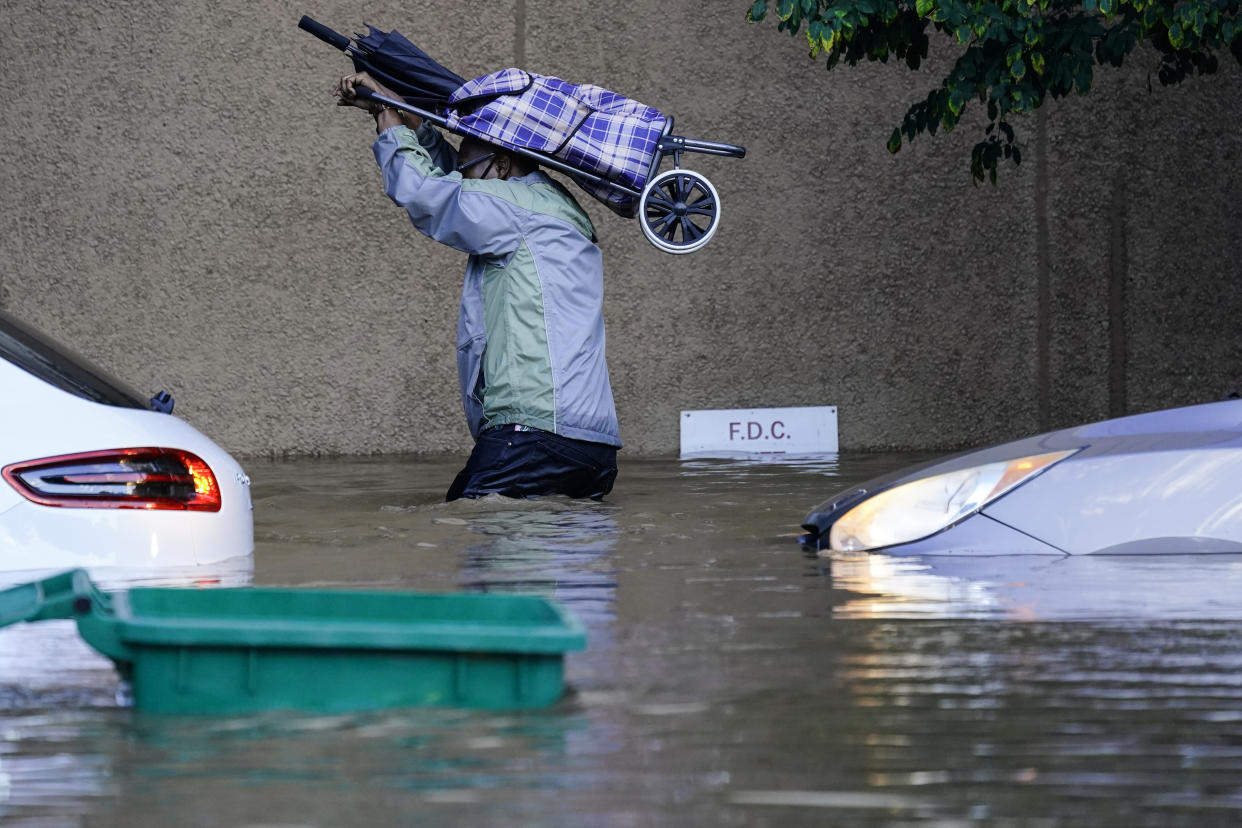 A resident waist-deep in floodwaters in Philadelphia on Thursday, passing submerged cars.