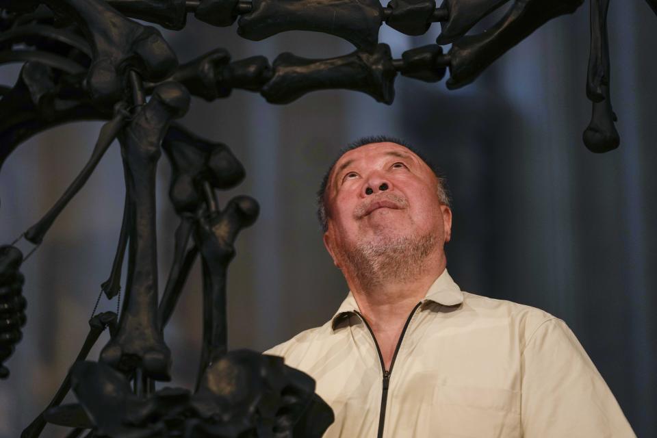 Chinese artist Ai Weiwei poses in front of his unveil glass body of work 'La Commedia Umana' a huge hanging glass sculpture otherwise referred to as a 'chandelier' at the San Giorgio deconsecrated church in Venice, Italy, Friday, Aug. 26, 2022. Chinese artist Ai Weiwei lampoons the surveillance culture and social media with his first ever glass sculpture, made on the Venetian island of Murano, that stands as a warning to the world: "Memento Mori,'' or Latin for "Remember You Must Die." (AP Photo/Luca Bruno)