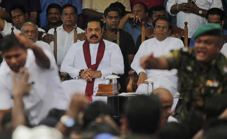 Sri Lankan president Maithripala Sirisena, right, and his newly appointed prime minister Mahinda Rajapaksa, center attend a rally held out side the parliamentary complex as police officer tries to control the crowd in Colombo, Sri Lanka, Monday, Nov. 5, 2018.. Thousands of Sri Lankans marched Monday in support of a new government led by the country's former strongman, highlighting the political polarization in the Indian Ocean island nation. (AP Photo/Eranga Jayawardena)