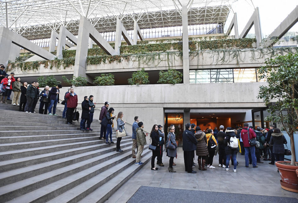 People line up at a Vancouver, British Columbia courthouse prior to the bail hearing for Meng Wanzhou, Huawei's chief financial officer on Monday, December 10, 2018. Meng Wanzhou, the chief financial officer of telecommunications giant Huawei and daughter of its founder, was detained at the request of the U.S. during a layover at the Vancouver airport on Dec. 1. (Jonathan Hayward/The Canadian Press via AP)