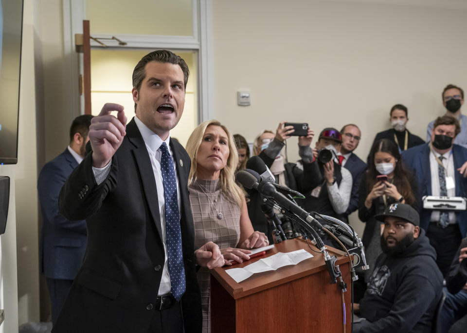 Rep. Matt Gaetz and Rep. Marjorie Taylor Greene stand at a podium, surrounded by reporters.