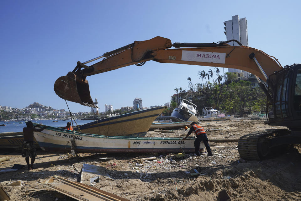 Residents remove a boat damaged by Hurricane Otis, in Acapulco, Mexico, Sunday, Nov. 12, 2023. Nearly three weeks after the Category 5 hurricane devastated this Pacific port, leaving at least 48 people dead and the city's infrastructure in tatters, the cleanup continues. (AP Photo/Marco Ugarte)