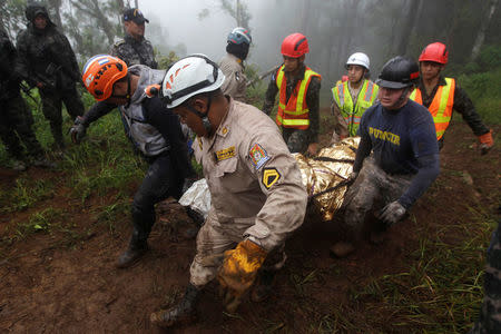 Rescue workers carry a body found in the area where Hilda Hernandez, the sister of Honduran President Juan Orlando Hernandez, and five others died when the helicopter they were traveling in crashed in San Matias, Honduras, December 17, 2017. REUTERS/ Jorge Cabrera