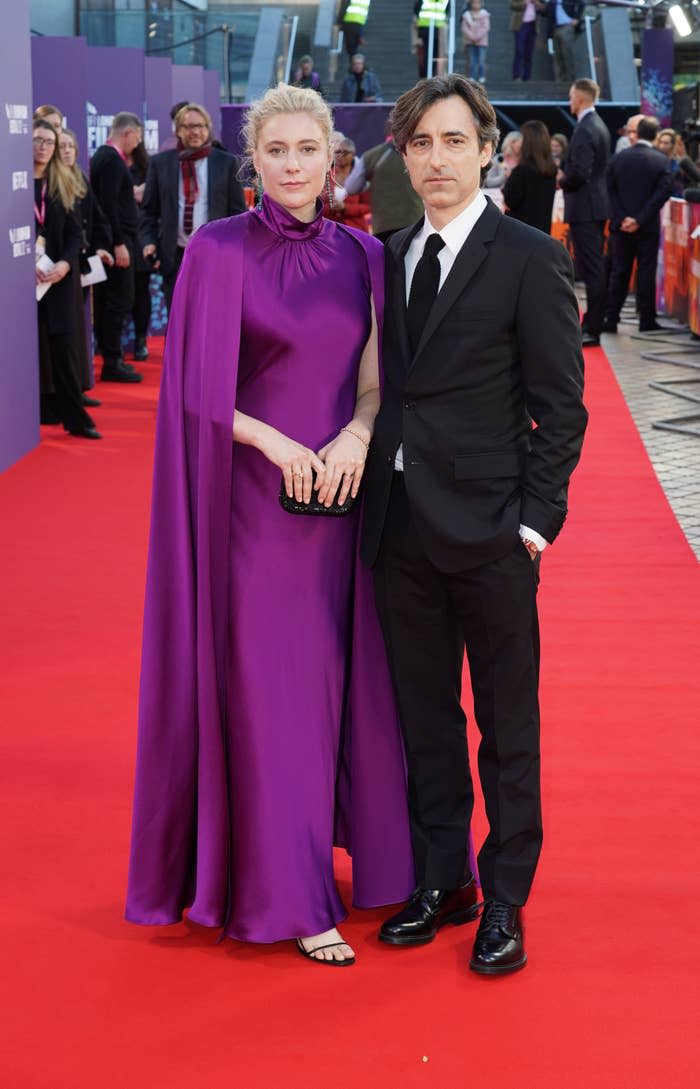 The couple stand on the red carpet at an event as photographers take their picture