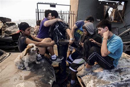 Residents, whose home was damaged by a major fire, visit what's left of their house in Valparaiso, April 13, 2014. REUTERS/Lucas Ninno