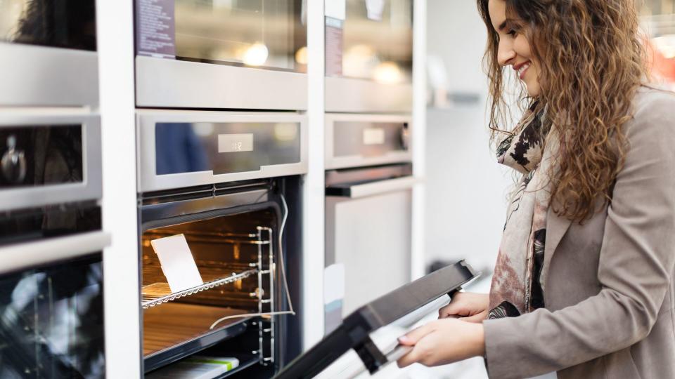 Woman buying stove in electronics store, opening stove.