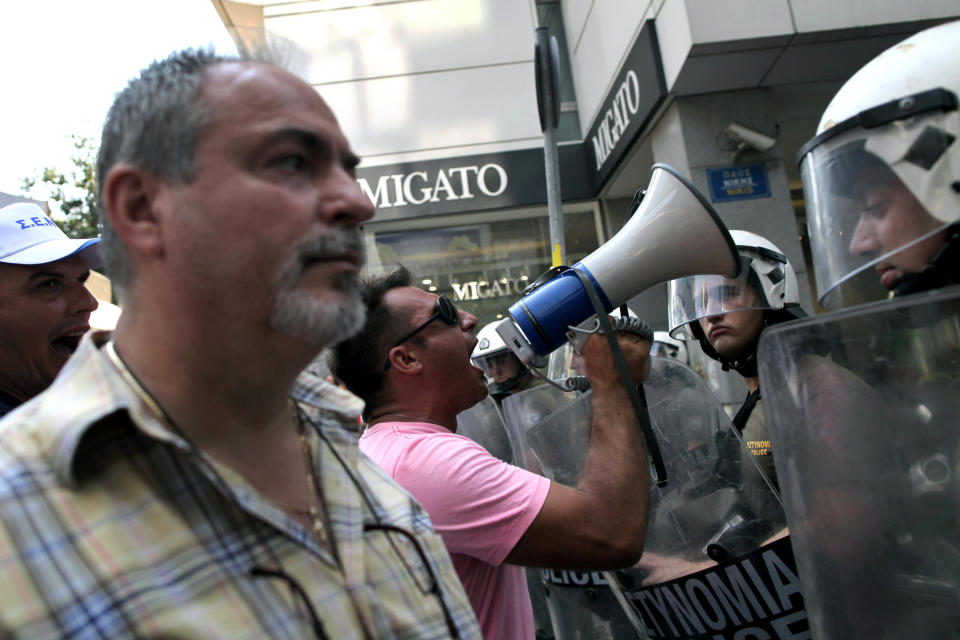 Striking shipyard workers chant slogans in front of riot police during a protest demanding jobs in their sector, outside the Greek Finance ministry in Athens on Tuesday, July 10, 2012. Greece has had to impose harsh austerity measures, including big cuts to pensions and salaries, to secure billions of euros worth of rescue loans from the IMF and other European countries that use the euro, to avoid bankruptcy.(AP Photo/Petros Giannakouris)