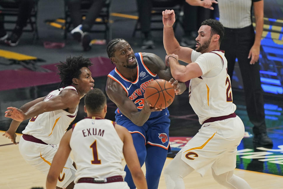 New York Knicks' Julius Randle, center, tries to get past Cleveland Cavaliers' Collin Sexton, left, Larry Nance Jr., right, and Dante Exum in the first half of an NBA basketball game, Tuesday, Dec. 29, 2020, in Cleveland. (AP Photo/Tony Dejak)