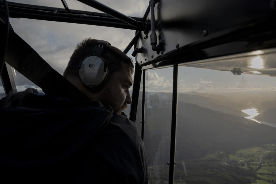 Garrett Fisher, an American aviator and adventurer, looks out the window of his plane while on a mission to photograph glaciers in Norway, on July 29, 2022. “In 100 or 200 years, most of them will be gone or severely curtailed,” he says. “It is the front line of climate change … the first indication that we’re losing something.” (AP Photo/Bram Janssen)
