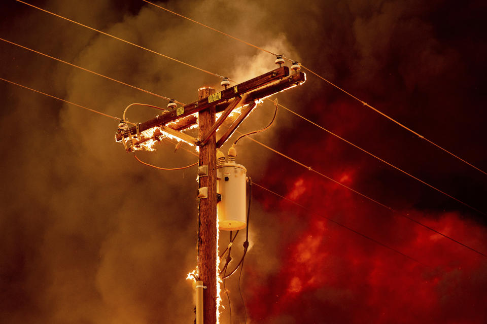 Fire burns along a power pole as the Sugar Fire, part of the Beckwourth Complex Fire, tears through central Doyle, Calif., on Saturday, July 10, 2021. (AP Photo/Noah Berger)