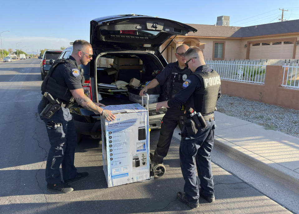 In this image provided by the Surprise, Ariz., Police Department, Surprise Police Department officers deliver an an air conditioner purchased for two elderly sisters, Paula Martinez, 93, and Linda Martinez, 87, they found sweltering inside their old home in 114 degrees F. (46 C.), Friday, July 14, 2023, in Surprise, Az. Efforts to protect older vulnerable people like the Martinez sisters during hot weather have increased in Arizona in recent years following the heat associated death five years ago of 72-year-old Stephanie Pullman in the Sun City West retirement community after her electricity company Friday, July 14, 2023, in Surprise, Ariz. (Surprise Police Department via AP)