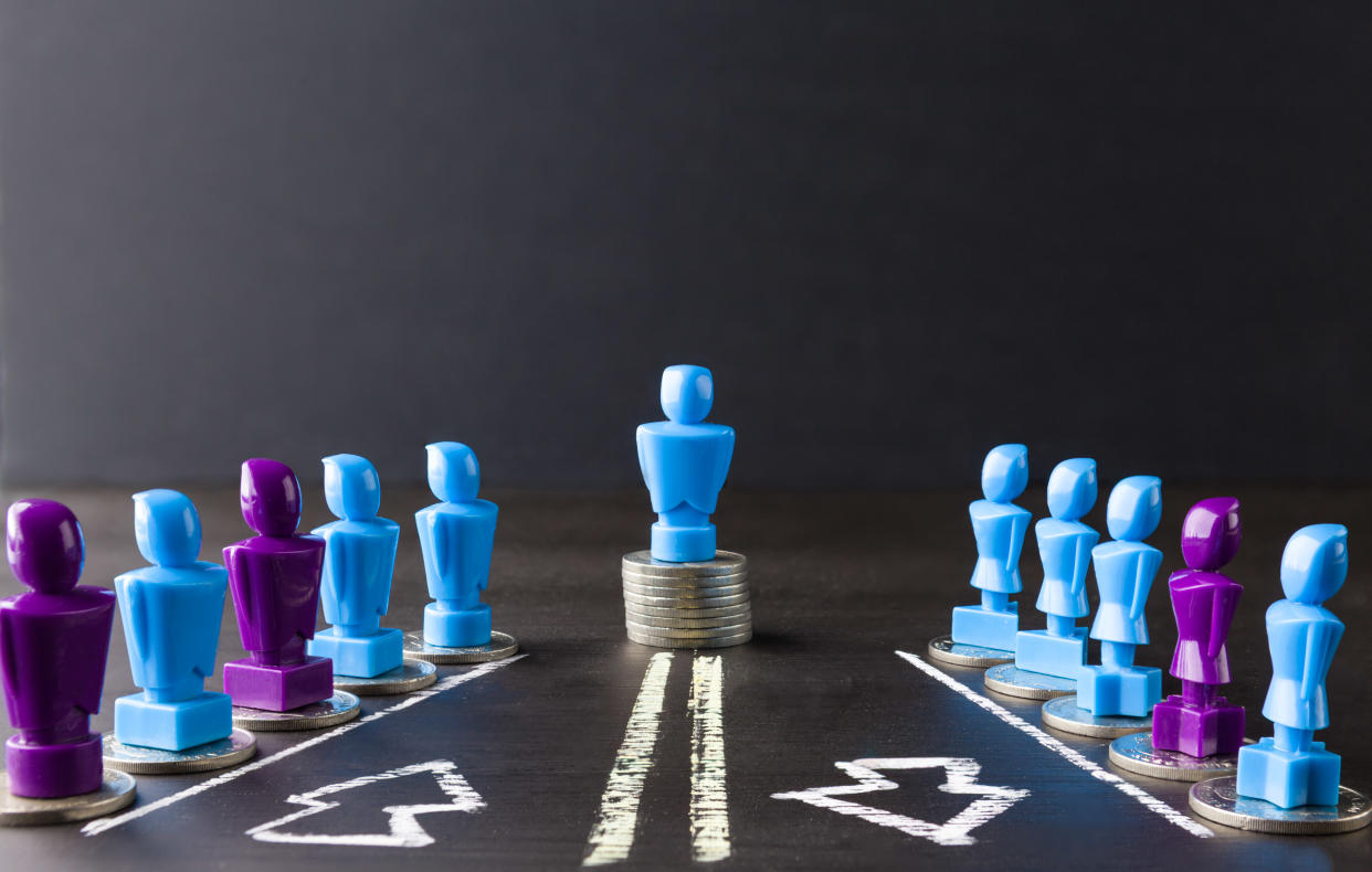 Leadership, money, wage, and gender equality concept depicted with female and male figurines standing on top of coins. Photo: Getty