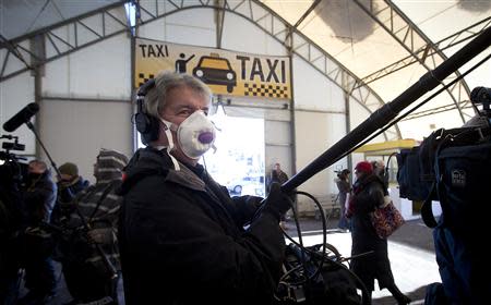 A member of the media wears a face mask as he holds a boom pole after Royal Caribbean's cruise ship, Explorer of the Seas arrived back at Bayonne, New Jersey January 29, 2014. REUTERS/Carlo Allegri