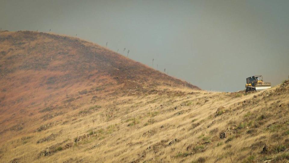 A bulldozer cuts a fire line on ridge above the SLO County Probation Department as firefighters battled a quick-moving wildfire in the hills above San Luis High School on Oct. 30, 2023.