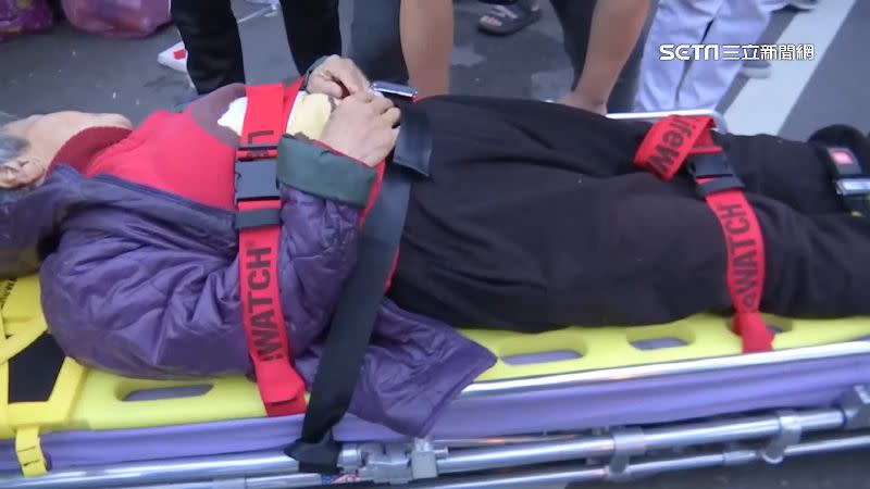 一名婦人在進香路線上倒下，救護人員緊急將她抬上擔架。