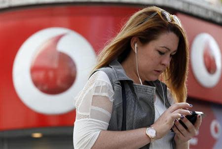 A woman talks on her mobile phone as she walks past a Vodafone store in London September 2, 2013. REUTERS/Stefan Wermuth