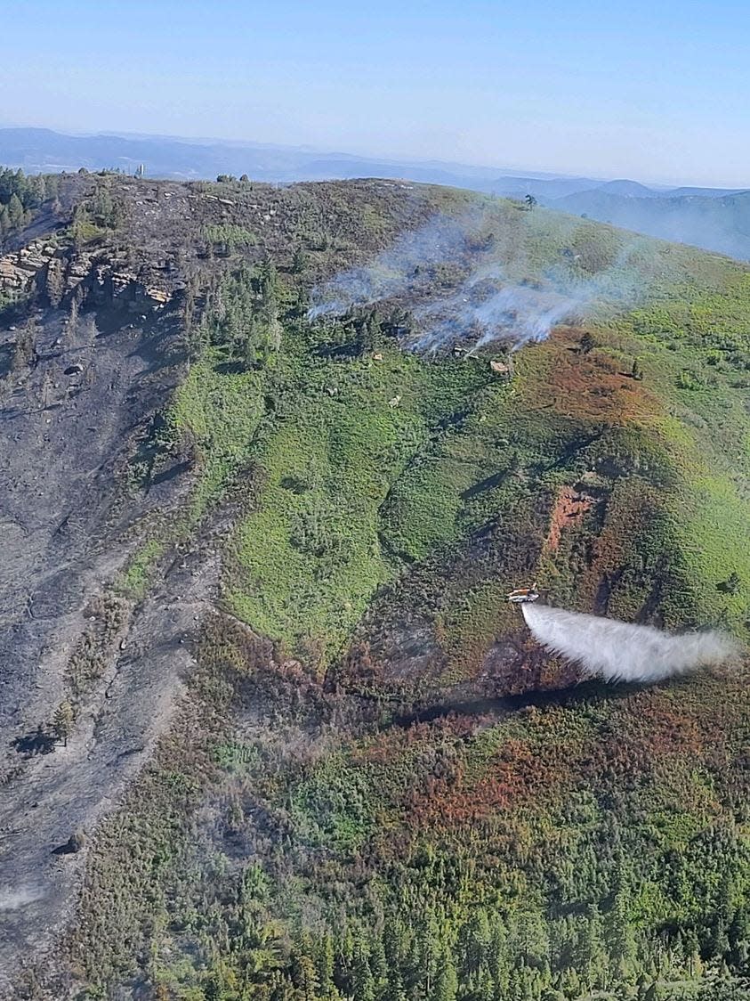 A Chinook helicopter drops water on the Perins Peak Fire. Red streaks of retardant from air tankers line the fire's flanks in a photo released by the Durango Interagency Fire Dispatch on their Facebook page May 25.