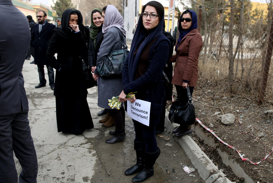 An Afghan member of a civil society organization, center, holds flowers outside of the La Taverna du Liban restaurant, during an anti terrorism demonstration in Kabul, Afghanistan, Sunday, Jan. 19, 2014. Hundreds of Afghans gathered outside a Lebanese restaurant in Kabul on Sunday to protest against Taliban attack that killed 21 people. The assault Friday by a Taliban bomber and two gunmen against the La Taverna du Liban restaurant was deadliest single attack against foreign civilians in the course of a nearly 13-year U.S.-led war there now approaching its end. They chanted slogans against terrorism as they laid flowers at the site of the attack. The dead included 13 foreigners and eight Afghans, all civilians. The attack came as security has been deteriorating and apprehension has been growing among Afghans over their country's future as U.S.-led foreign forces prepare for a final withdrawal at the end of the year. (AP Photo/Massoud Hossaini)