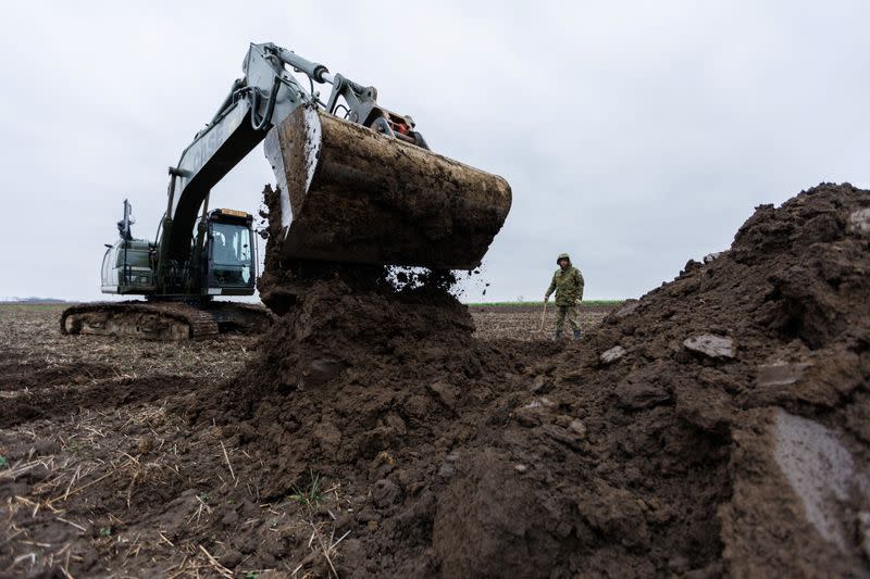 Croatian soldier is seen next to excavators during digging on newly discovered mass grave with 11 bodies near Vukovar