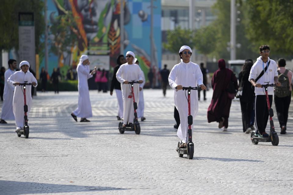 People ride an e-scooter through the COP28 U.N. Climate Summit, Friday, Dec. 8, 2023, in Dubai, United Arab Emirates. (AP Photo/Rafiq Maqbool)