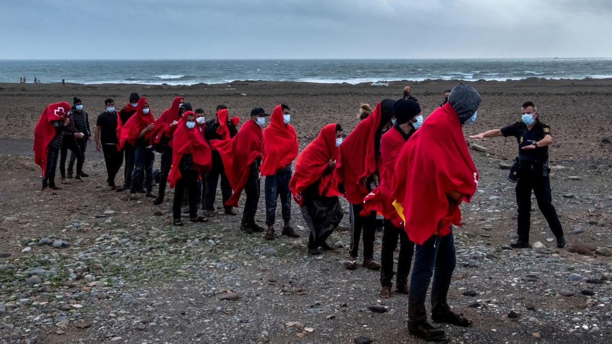 Migranten aus Marokko stehen an einem Strand auf Gran Canaria, nachdem sie den Atlantik mit einem Holzboot überquert haben.