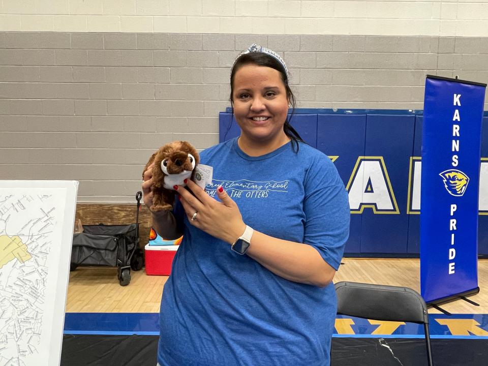 Lindsay Day, secretary for the new Mill Creek Elementary School, shows off the new mascot, a stuffed otter, at the 70th annual Karns Community Fair at Karns High School on July 15, 2023.