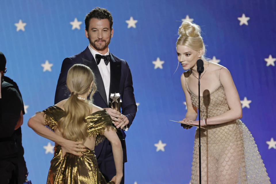 Amanda holds the back of her dress while walking on stage