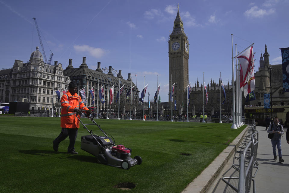 A worker cuts grass outside the Houses of Parliament in London, Wednesday, May 3, 2023. The Coronation of King Charles III will take place at Westminster Abbey on May 6. (AP Photo/Kin Cheung)