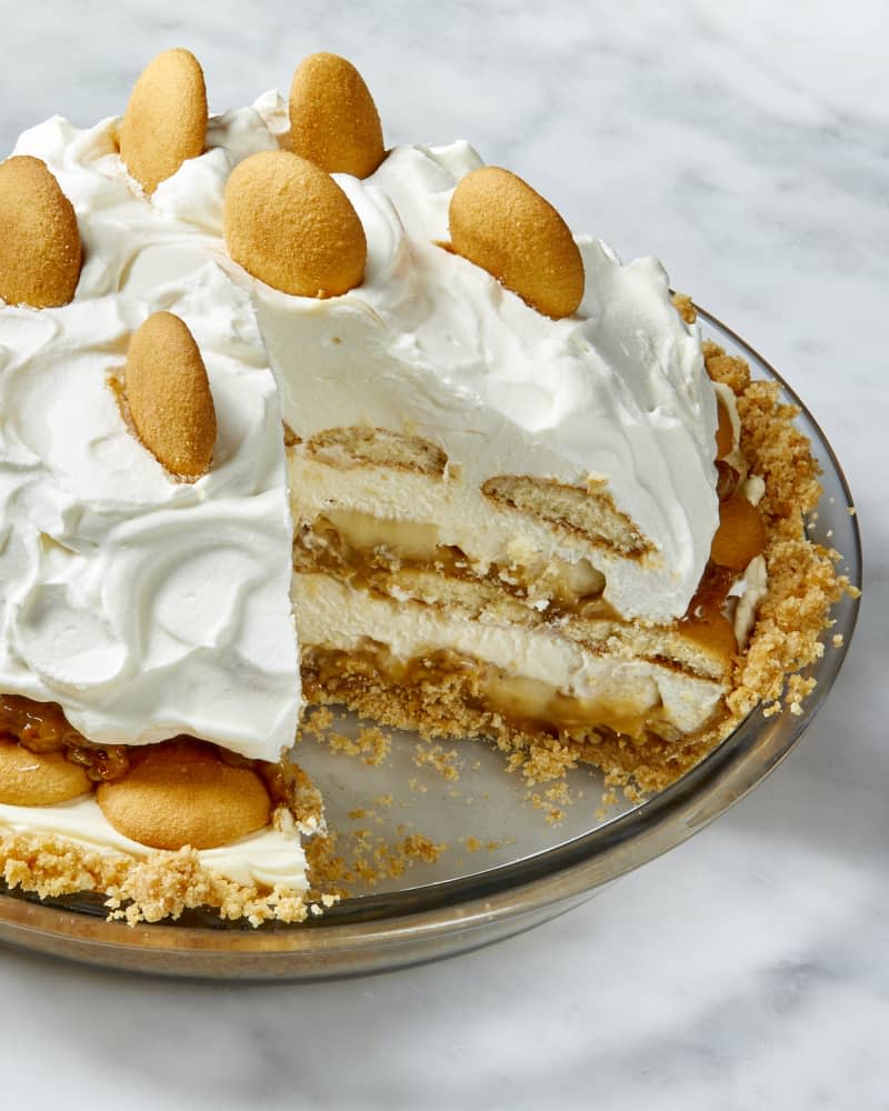 Angled view of banana pudding pie in a glass pie plate, with one slice taken out.