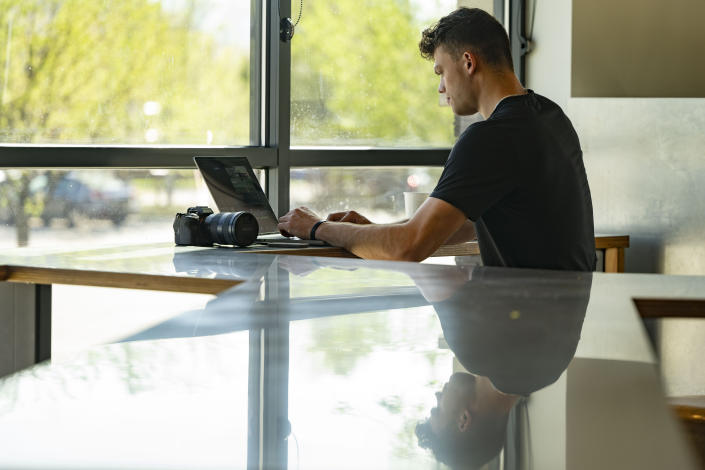 Adam Botkin, a football TikTok influencer, edits a video for a post at a Chipotle Mexican Grill while eating dinner in Missoula, Mont., on Wednesday, May 3, 2023. Botkin, a former walk-on place kicker and punter for the Montana Grizzlies, gained notoriety on the social media platform after videos of him performing kicking tricks went viral. (AP Photo/Tommy Martino)