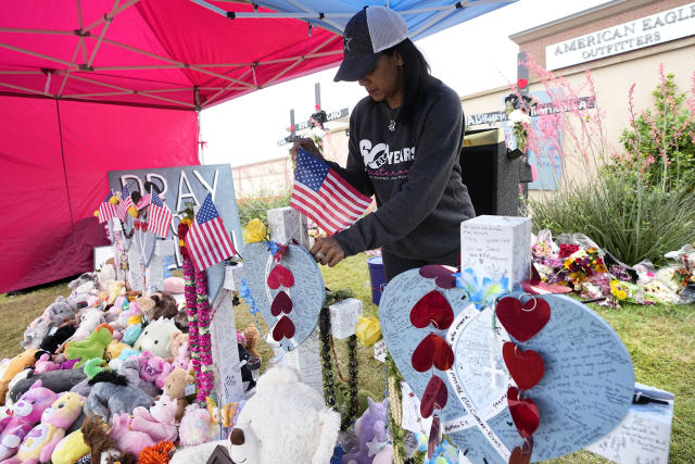 Inga VanWagoner of Allen, Texas, who served in he U.S. Army, places flags atop crosses at a makeshift memorial by the mall where several people were killed, Wednesday, May 10, 2023, in Allen, Texas. (AP Photo/Tony Gutierrez)