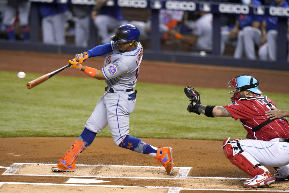 New York Mets' Francisco Lindor hits a double next to Miami Marlins catcher Sandy Leon durning the first inning of a baseball game Friday, May 21, 2021, in Miami. (AP Photo/Lynne Sladky)